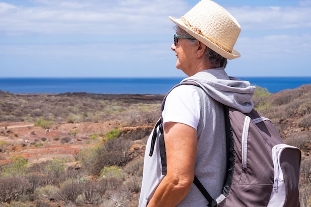 Cheerful adult mature woman during outdoor leisure activity trekking at sea - freedom holiday vacation in nature