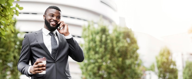 Cheerful african american employee talking on mobile phone having coffee break