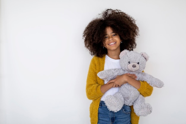 Cheerful african american girl posing with her toy on white