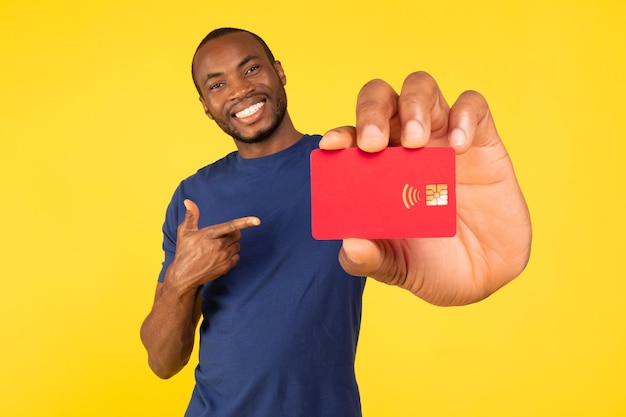 Cheerful African American Guy Showing Credit Card On Yellow Background