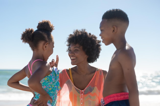 Cheerful african american mother with son and daughter enjoying summer holiday at beach