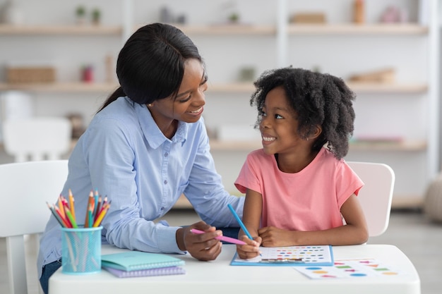 Cheerful african american teacher and little girl exercising