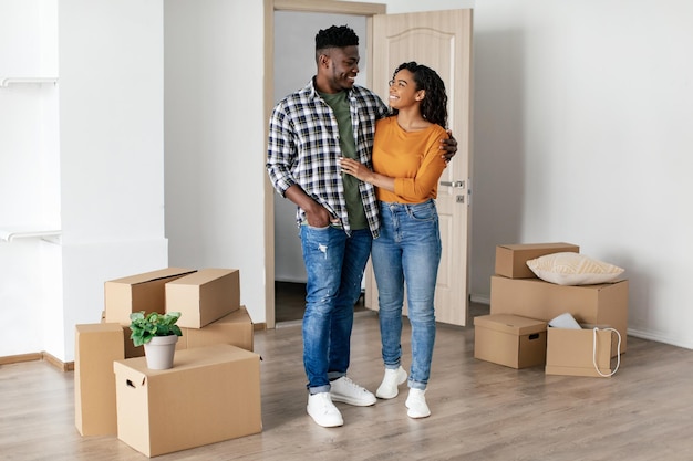 Cheerful african couple embracing standing after relocation in new home