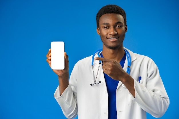 Cheerful african doctor using mobile phone over blue studio background