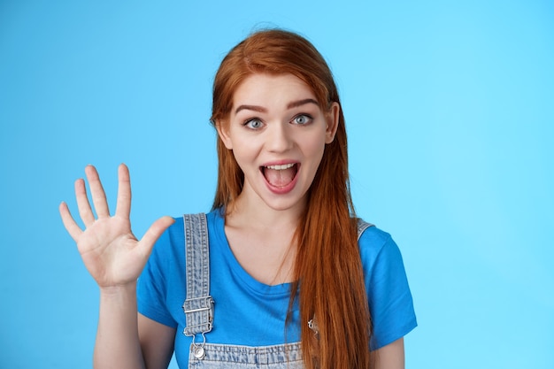 Cheerful amused redhead woman long natural red hairstyle show number five fifth, make order, counting fingers, smiling broadly, talking amused, count down, stand blue background joyful