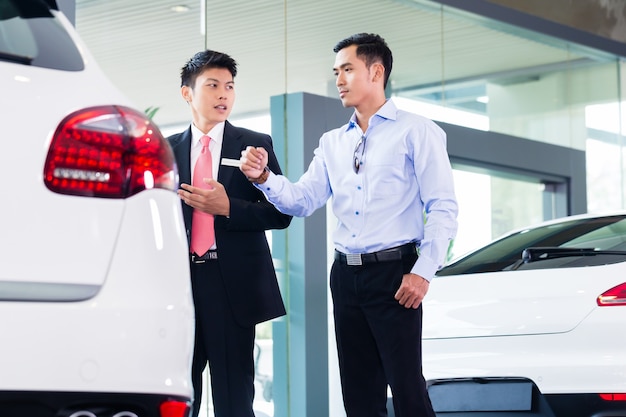 Cheerful Asian Car Salesman selling auto to customer