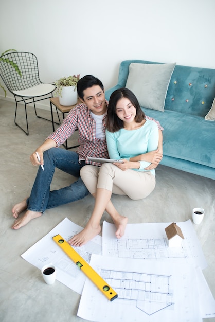 Cheerful asian couple looking at construction house plan