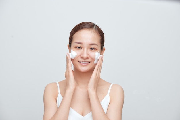 Cheerful Asian female woman applying foaming cleanser, has clean fresh healthy skin.