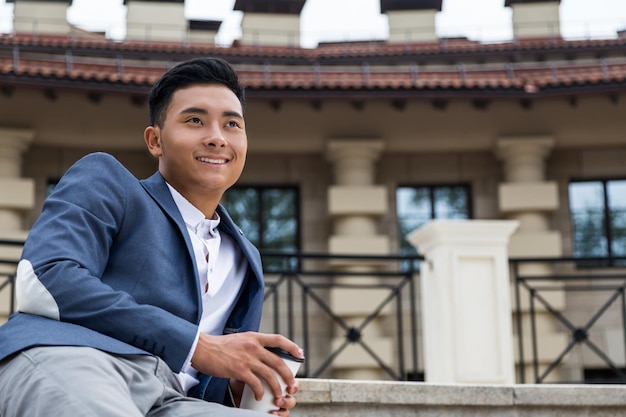 Cheerful Asian man with cup of coffee