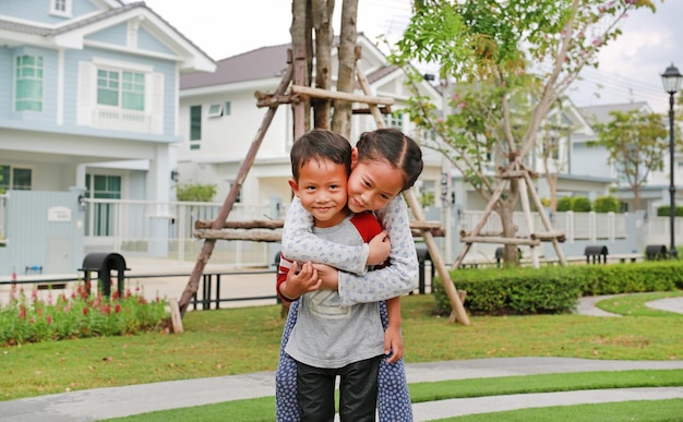 Cheerful Asian sister hugging her little brother in the garden Young girl child cuddle little boy