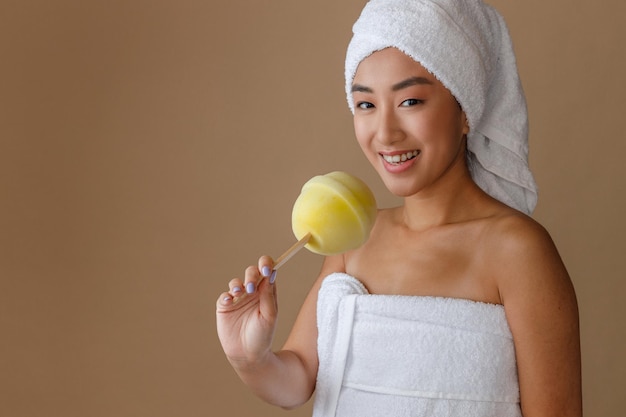 Cheerful asian woman holding lollipop bath sponge