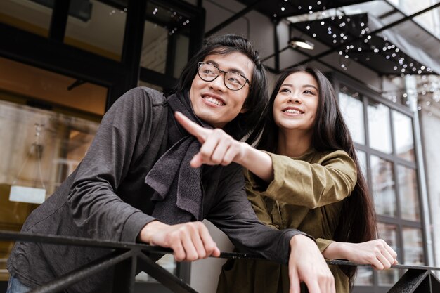 Cheerful asian young loving couple standing near cafe outdoors