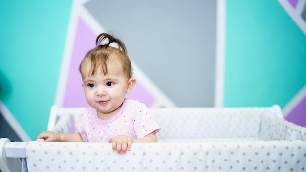 Cheerful baby standing in cradle