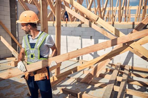 Cheerful bearded male person turning head while looking aside at his foreman on the construction site