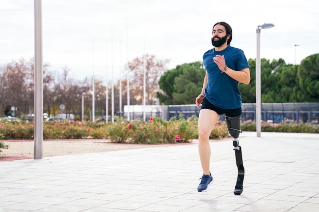 Photo cheerful bearded runner with advanced carbon fiber prosthetic leg enjoying a run in a scenic park