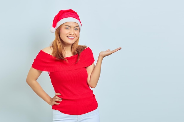 Cheerful beautiful asian woman wearing christmas dress showing copy space in palms on white background