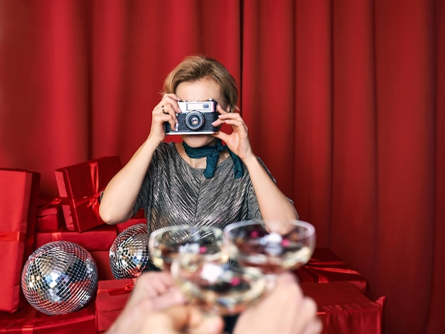 Cheerful beautiful photographer woman at the party celebration on red curtains background