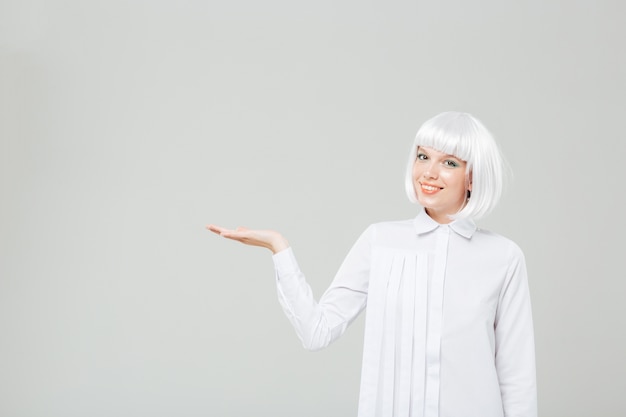 Cheerful beautiful young woman in blonde wig holding copyspace on palm