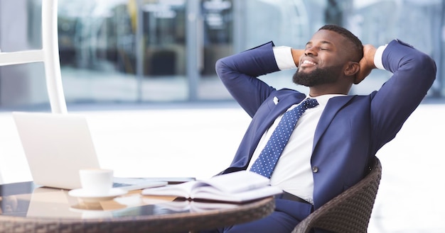 Cheerful black businessman relaxing in outdoor cafe panorama