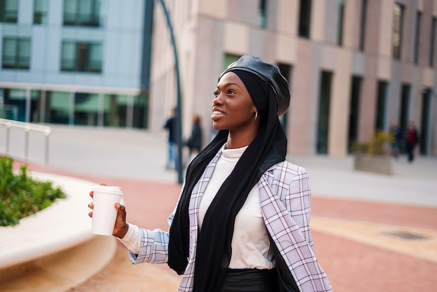 Cheerful black lady with takeaway beverage in park