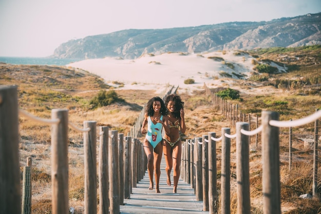 Cheerful black women running on pier