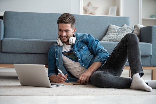 Cheerful blogger. Handsome modern man designer working on laptop online, using internet at home