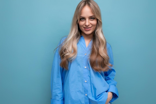 Photo cheerful blond girl in a blue shirt isolated on a blue background