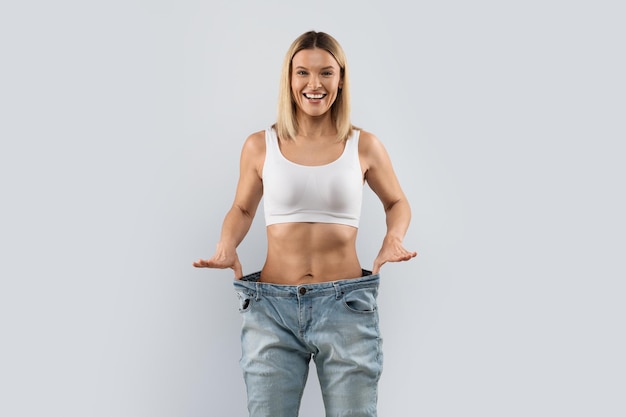 Cheerful blonde woman wearing big pants and smiling