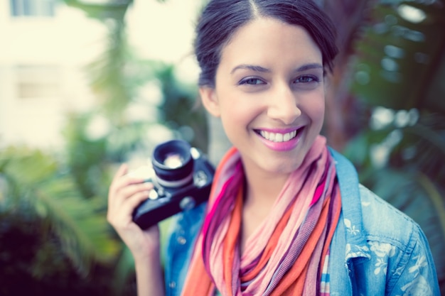 Cheerful brunette photographer standing outside smiling at camera