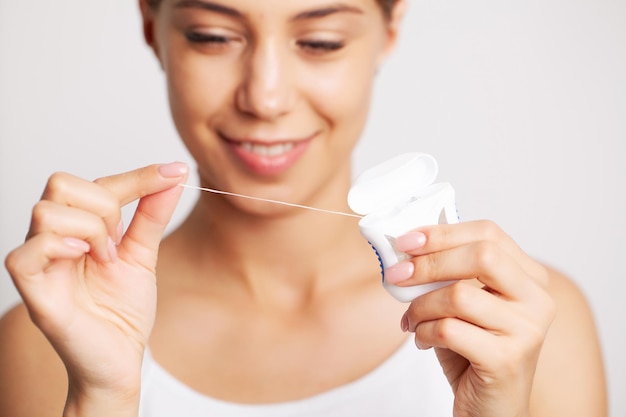 Cheerful brunette woman using dental floss in bathroom