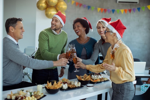 Cheerful business colleagues tasting with Champagne on New year's party in the office