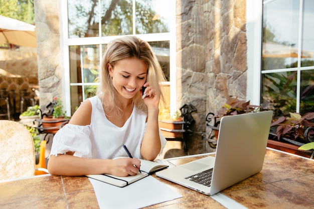 Cheerful businesswoman talking by cellphone, while sitting at the cafe