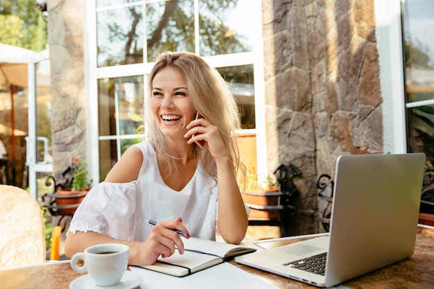 Cheerful businesswoman talking by cellphone, while sitting at the cafe