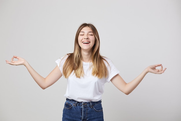 Cheerful and calm girl dressed in a white t-shirt and jeans is on a white background in the studio .