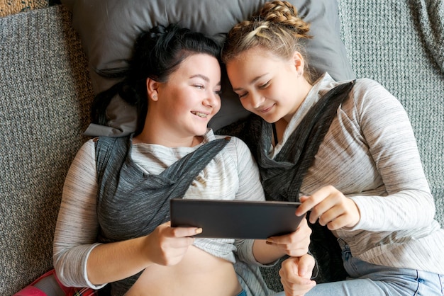 Cheerful caucasian girls sisters lie on floor and watch funny videos