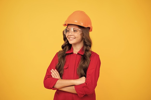 Cheerful child girl in protective hard hat crossed hands future career