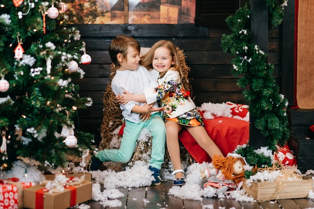 Cheerful children hugging in studio with christmas tree and new year decorations.