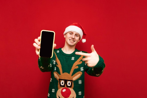 Cheerful christmas guy with smartphone in his hand isolated