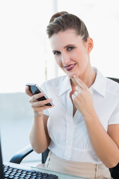 Cheerful classy businesswoman using smartphone