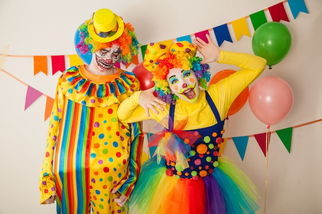 Cheerful clown and a scary clown at a colorful party