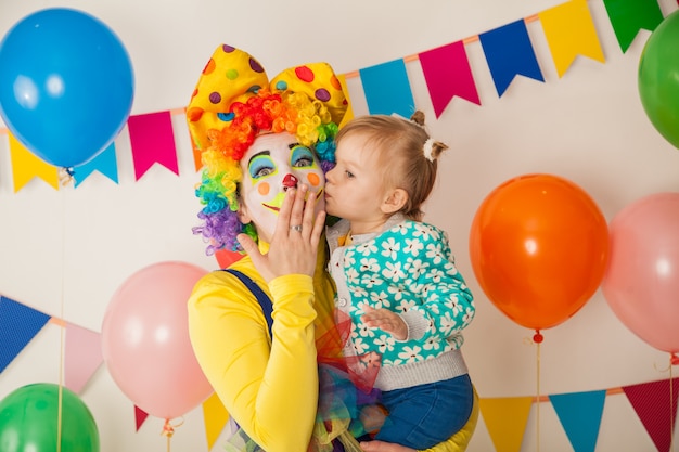 Cheerful clown with a kid at a colorful party