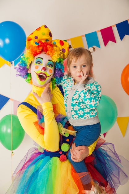 Cheerful clown with a kid at a colorful party