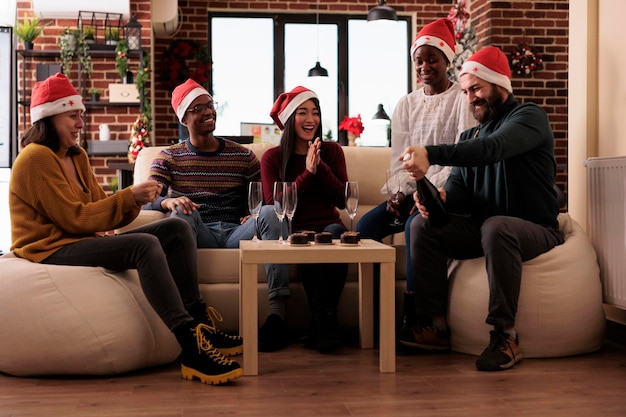 Cheerful colleagues drinking wine at christmas party, pouring alcohol in glasses to celebrate winter holiday festivity in workplace with xmas decorations and festive ornaments.