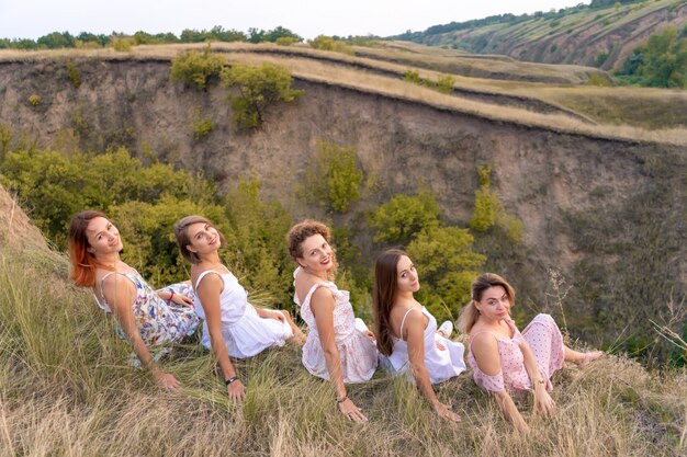 Photo a cheerful company of womans friends enjoy a picturesque landscape of the green hills at sunset