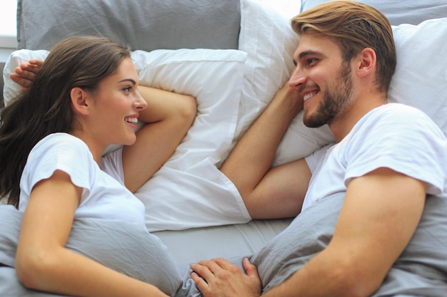 Cheerful couple awaking and looking at each other in bed