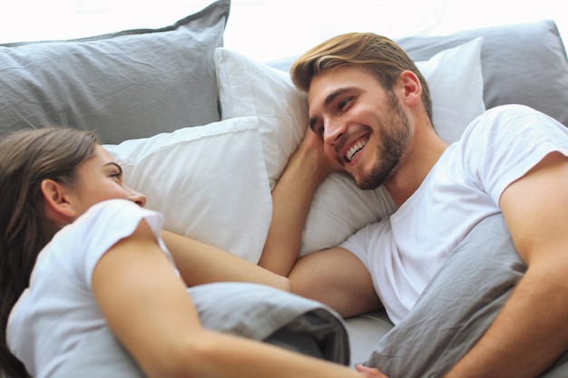 Cheerful couple awaking and looking at each other in bed