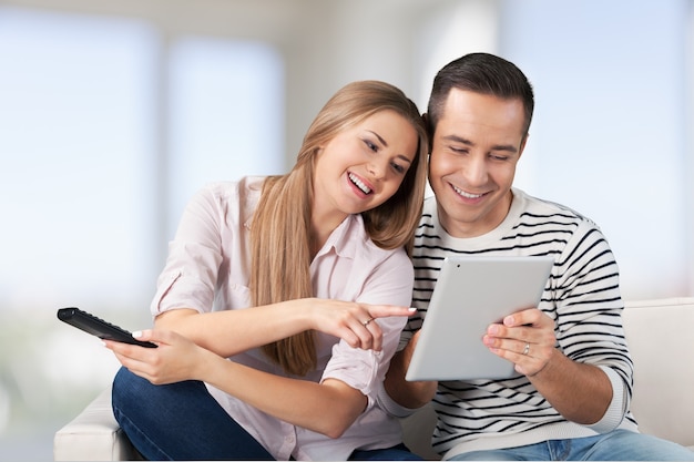 Cheerful couple choosing tv program on digital tablet