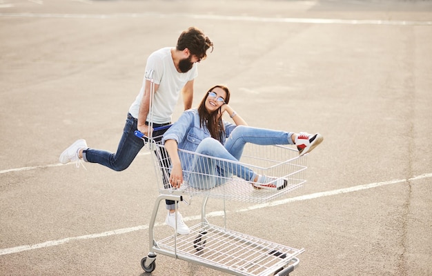 Cheerful couple having fun with shopping cart