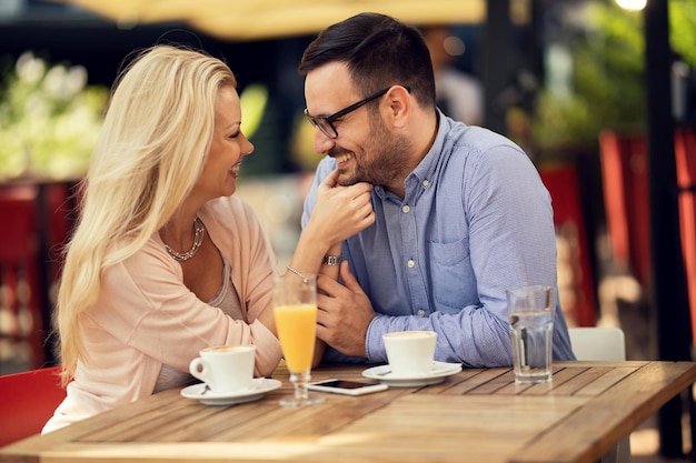 Cheerful couple in love sitting close to each other and talking on a date in a cafe