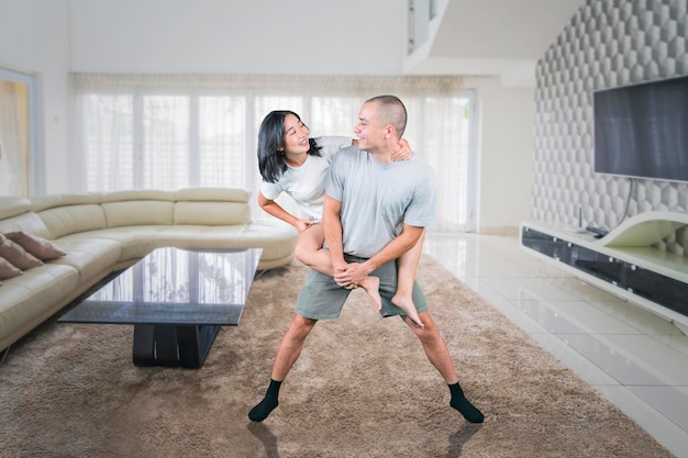 Cheerful couple playing a piggyback ride at home